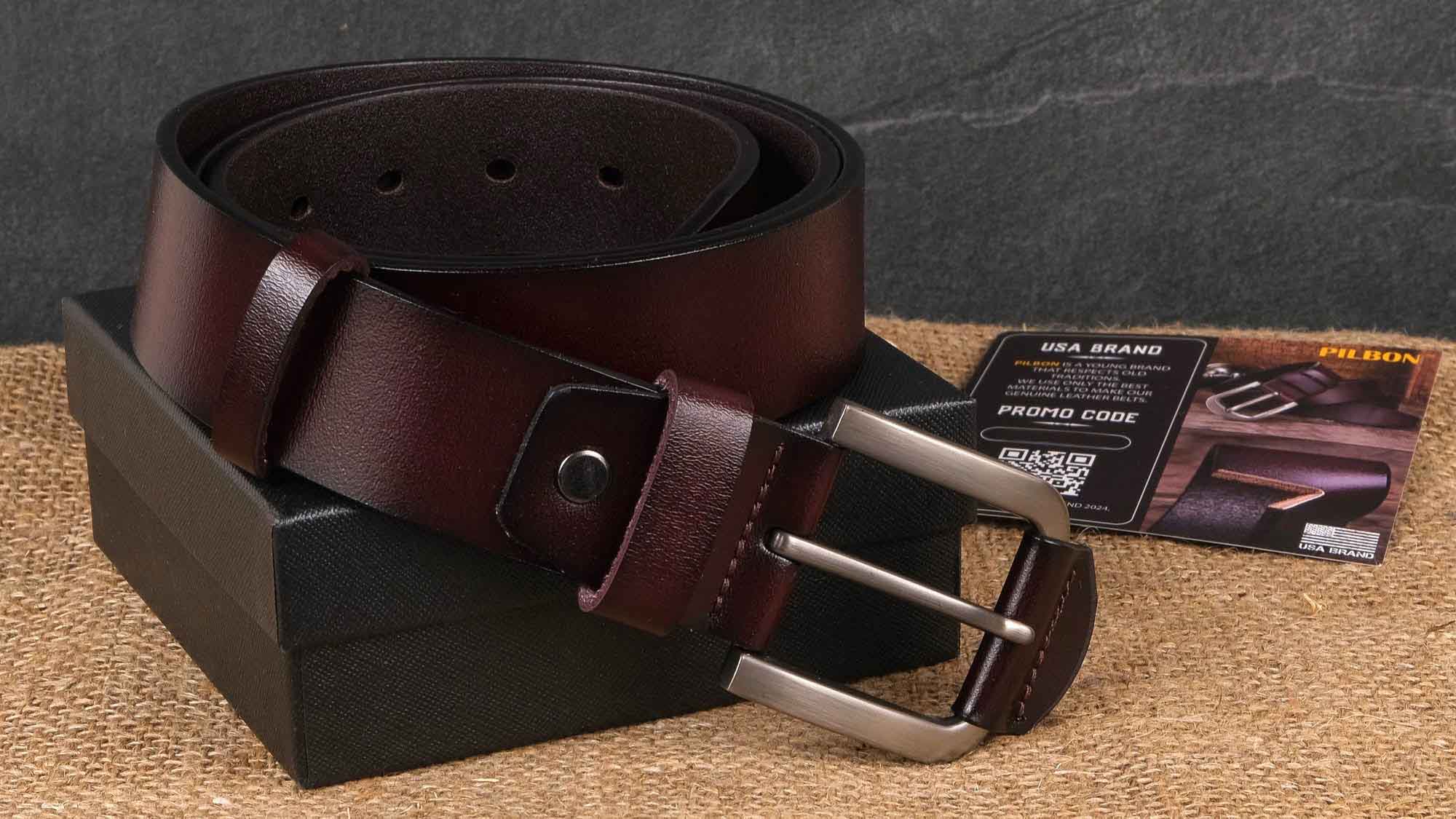 Brown leather belt with metal buckle resting on a box, accompanied by a promotional card and code.